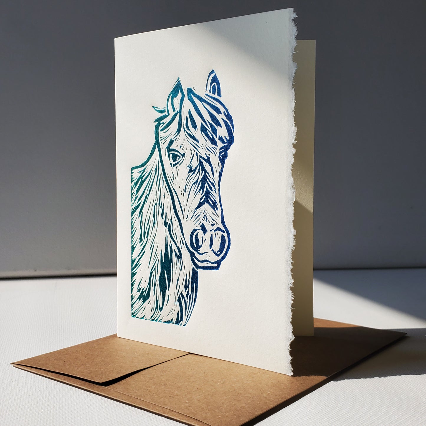 Janet Davis' Newfoundland Pony linocut relief print on a Norton's Cove Card in a blue-green rainbow roll.