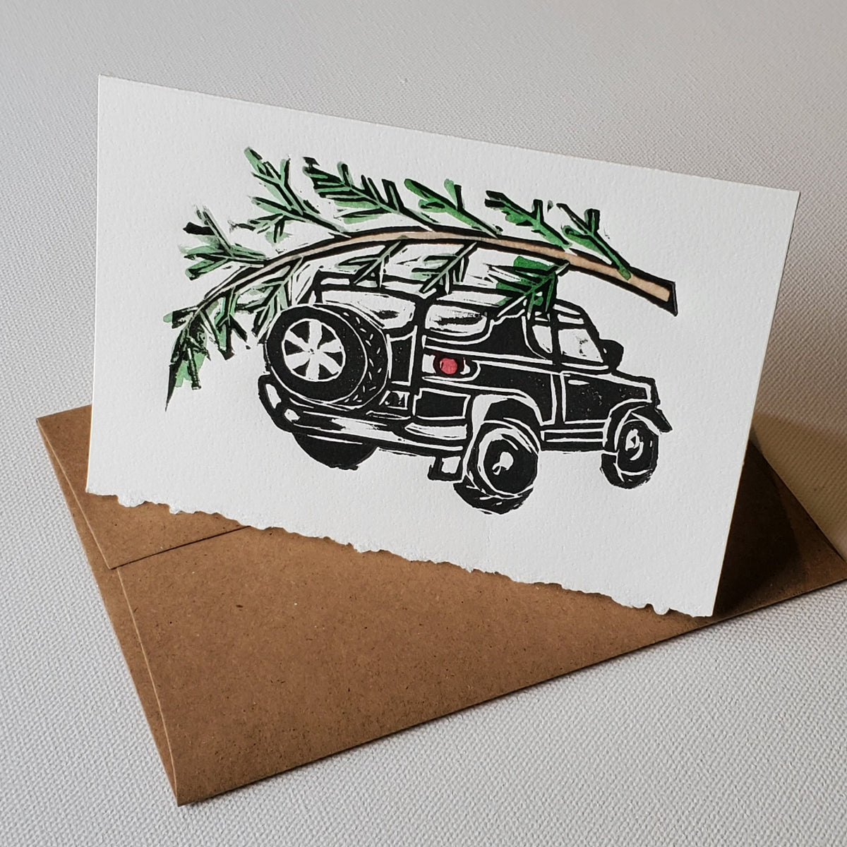2007 Toyota FJ Cruiser with Christmas Tree tied to the roof rack. This is an original lino-cut relief print by Janet Davis