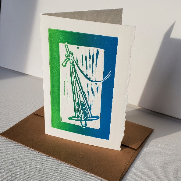 Linocut print Norton's Cove Card in Janet Davis' Killick design, shown in blue-green ink on a Kraft envelope