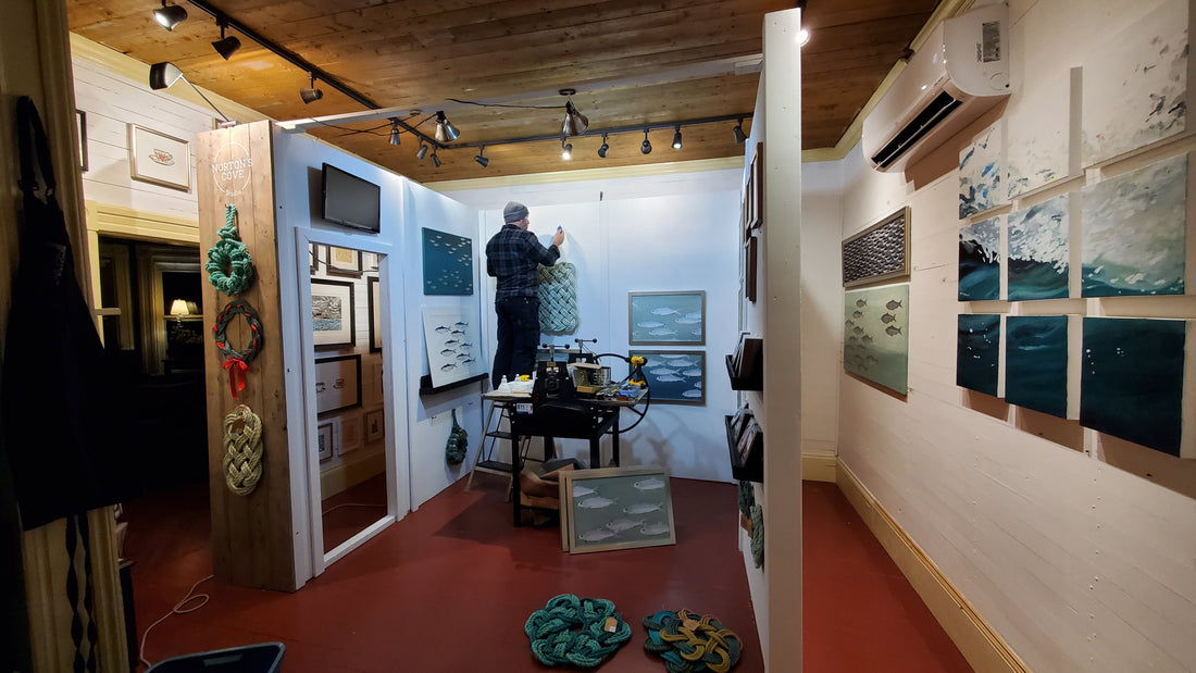 Duke placing screws on the booth walls to hold artwork 