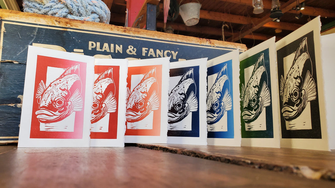 7 differently coloured Jacky Conner cards lined up on a wooden counter at Job Kean's Shop.