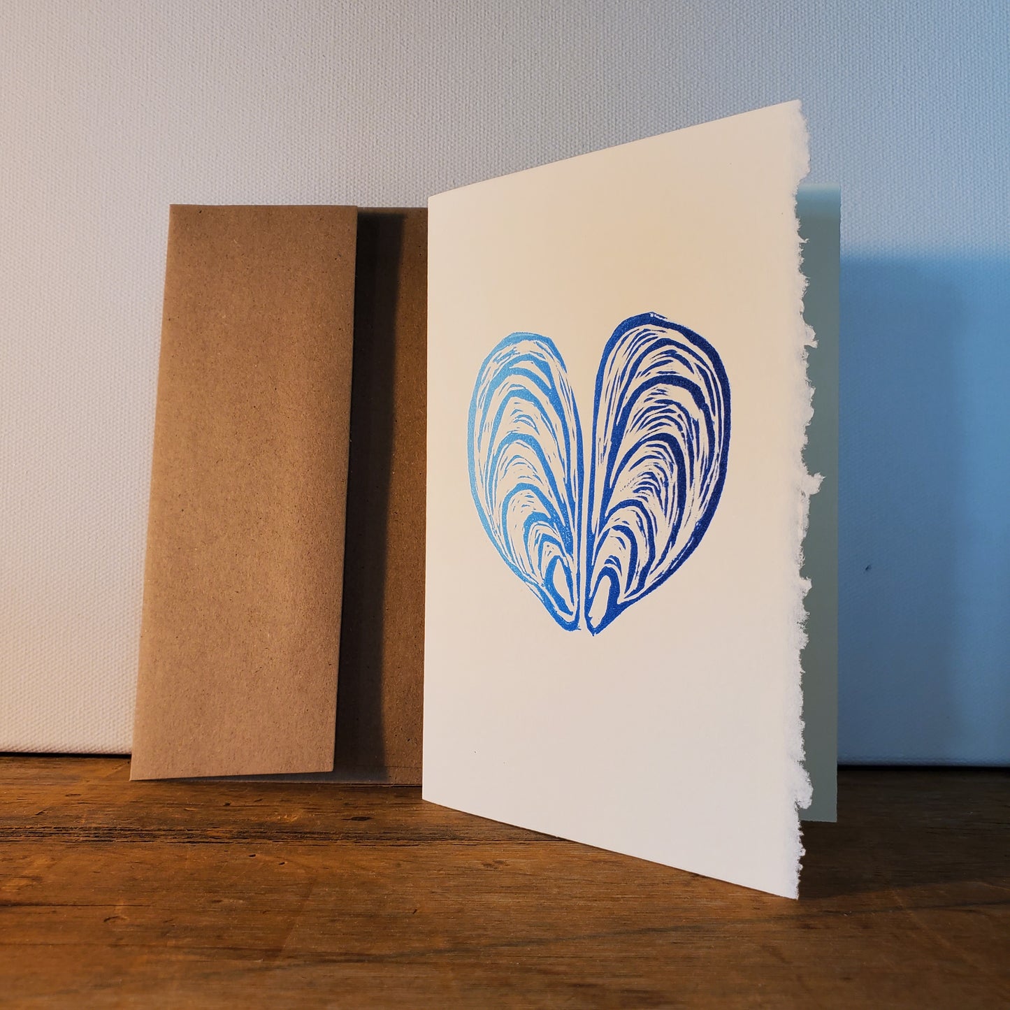 Card with blue shell design on a white background, placed on a wooden surface.