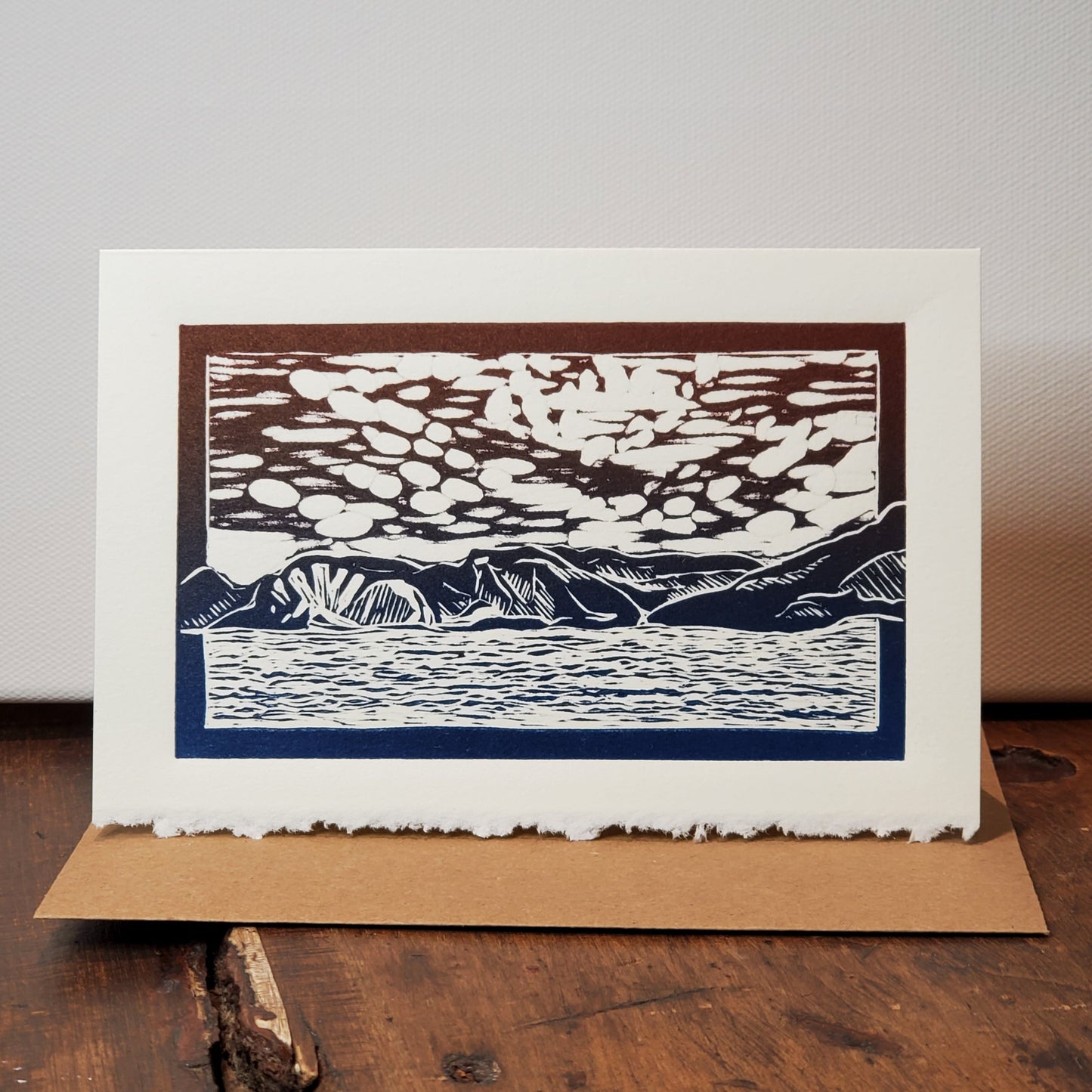 Norton's Cove Card in the Norris Point of View design photographed on the wooden counter with a stretched canvas as a backdrop.