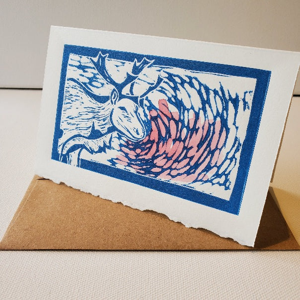 Rudolph, the red nosed caribou is printed in blue ink on antique white cotton paper with a natural decal edge at front-bottom.  Red watercolour suggests a glowing red nose.
