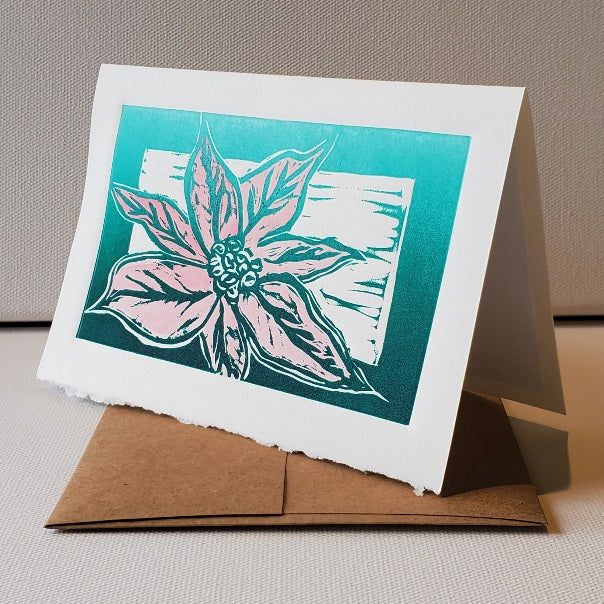 Poinsettia image linocut printed onto antique white paper with a natural decal edge at front/bottom.  Hand tinted with red water-colour.