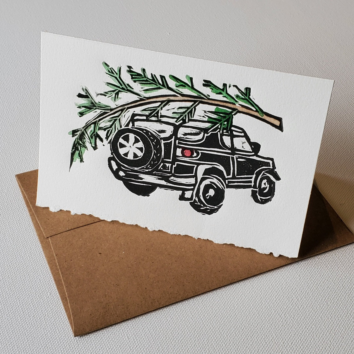 2007 Toyota FJ Cruiser with Christmas Tree tied to the roof rack.  This is an original lino-cut relief print by Janet Davis