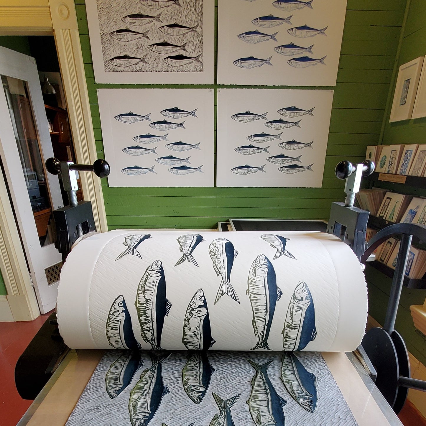 Editioning Smudge Herring: Just Keep Swimming at Norton's Cove Studio, August 2021.  Trial Proofs and BAT hanging on wall in background.  TP#1  upper left hand corner in b/w